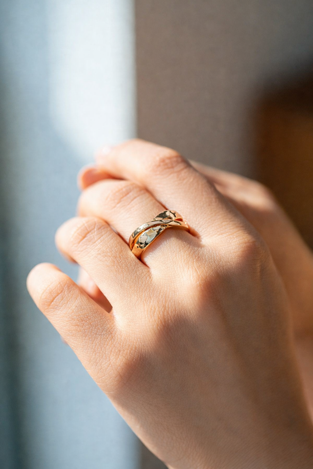 Close-up of Ramona gold criss-cross ring with hammered texture on a jewelry display.
