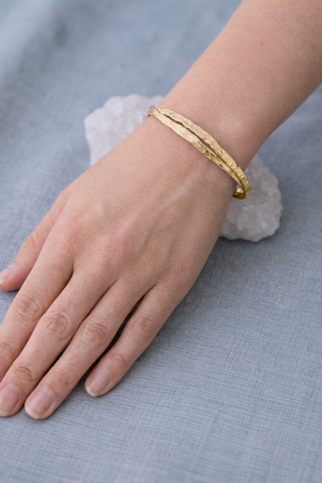 Model wearing the gold Twist Cuff showing the organic, light-reflecting hammered finish.