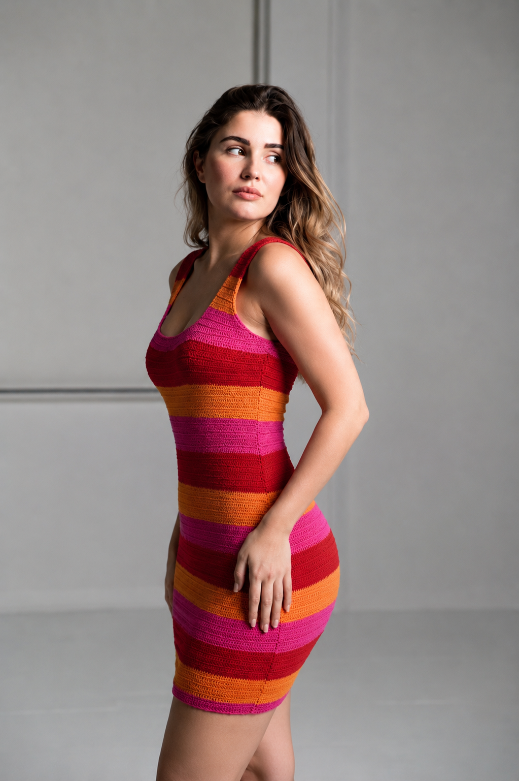 Side profile of a model looking back, wearing the colorful striped crochet knit MUMU Day Trip dress.