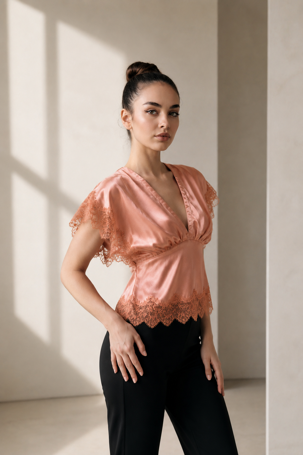 Portrait shot of a model in the rose Satin Lace Top, highlighting the delicate lace flutter sleeves.